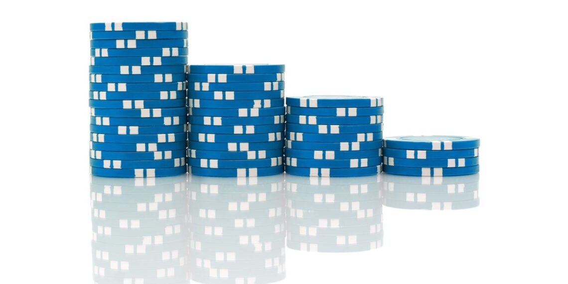 A series of blue and white Blue Chip poker chips stacked in descending order from left to right against a white background. The stacks reflect on the shiny surface below them. | 5StarsStocks