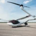 A sleek, white electric vertical takeoff and landing (eVTOL) aircraft with two large rotors is parked on an empty runway under a clear blue sky. With its futuristic design and dark-tinted windows, this marvel of aviation technology could soon be the darling of drone stocks investors. | 5StarsStocks