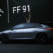 Sleek silver Faraday Future FF 91 electric SUV showcased indoors with a dark background and illuminated brand logo. The vehicle is side-facing, highlighting its modern design and stylish black wheels under soft ambient lighting—an exciting prospect akin to discovering the top penny stocks to buy now for June 2024. | 5StarsStocks