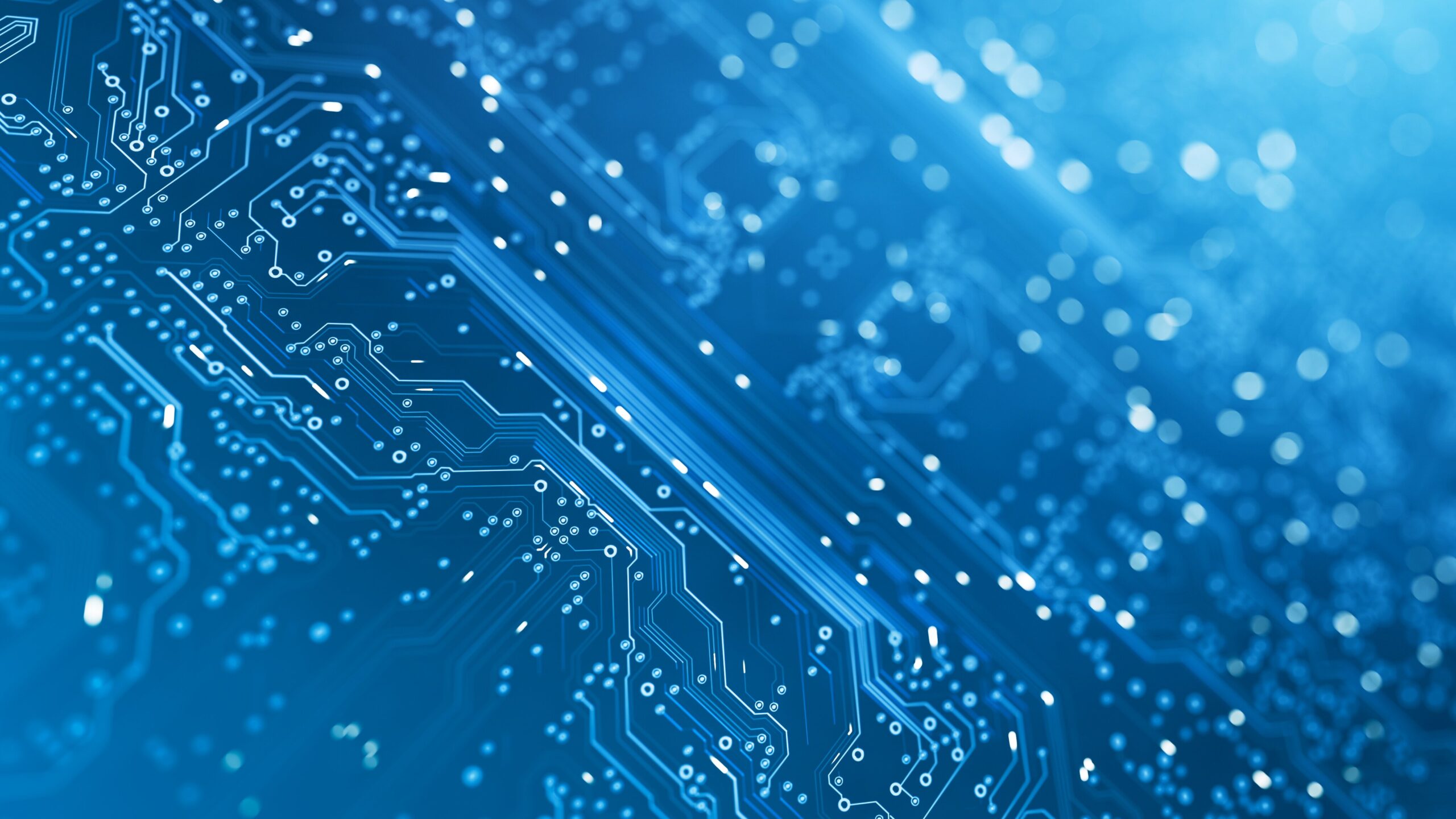 A close-up of a blue circuit board with intricate pathways and tiny embedded components. The background is filled with light bokeh, creating a futuristic and high-tech feel. The image emphasizes the complexity and precision reminiscent of leading technology stocks. | 5StarsStocks