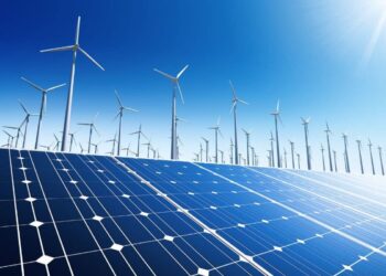 A field of solar panels in the foreground with numerous wind turbines scattered across the background under a clear blue sky. The scene depicts a renewable energy landscape, highlighting both solar and wind power generation, capturing the essence of renewable energy stocks' growth potential. | 5StarsStocks