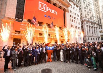 A jubilant crowd celebrates outside the New York Stock Exchange, marked by bright fireworks and two American flags. People are cheering, and a person is dressed as a character. A large banner on the building proudly reads "UiPath," highlighting its stock debut. | 5StarsStocks