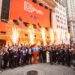 A jubilant crowd celebrates outside the New York Stock Exchange, marked by bright fireworks and two American flags. People are cheering, and a person is dressed as a character. A large banner on the building proudly reads "UiPath," highlighting its stock debut. | 5StarsStocks