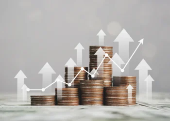 A stack of coins arranged in ascending order with white upward arrows and a line graph overlay, symbolizing financial growth and economic progress. The background is blurred with a light gray hue, reflecting robust financial health. | 5StarsStocks