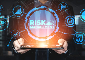 A person in a suit holds a tablet with the words "RISK MANAGEMENT" highlighted in the center. Surrounding icons represent various aspects of effective risk management, including charts, graphs, and financial symbols, all connected in a network-like design. | 5StarsStocks