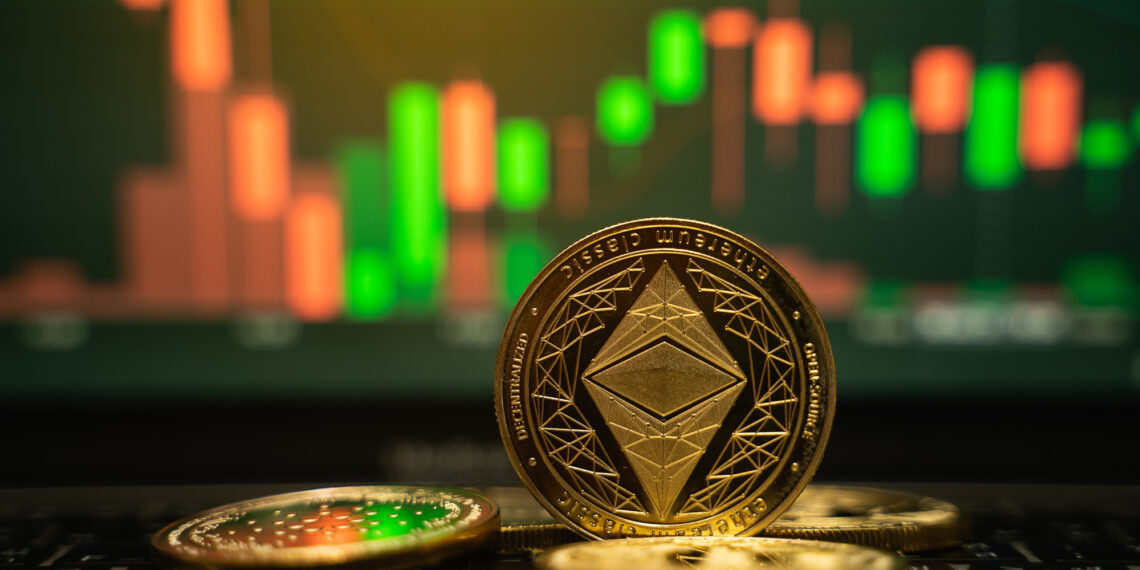 Close-up of Ethereum coins on a laptop keyboard with a stock market chart in the background. The chart displays green and red candlestick patterns, echoing crypto investment trends. The scene is dimly lit, highlighting the shiny coins. | 5StarsStocks