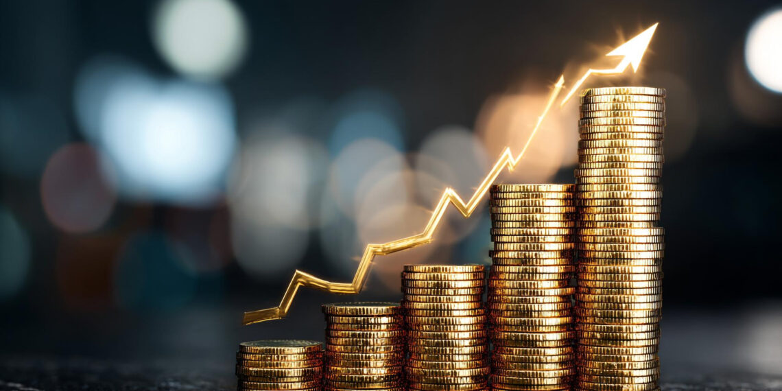 Stacks of gold coins arranged in ascending order with a glowing upward arrow graph above them, symbolizing financial growth or increasing profits. The background is blurred with bokeh lights. | 5StarsStocks