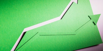 Two green paper arrows pointing upward symbolize growth or progress, set against a green background with shadows emphasizing the cut-out shapes. | 5StarsStocks