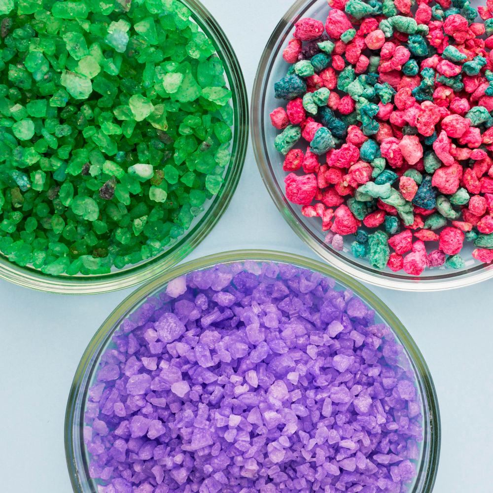 Three round glass dishes filled with coarse, colorful crystals—green in the top left, red and green mixed in the top right, and purple at the bottom—are set on a light blue background, evoking a vibrant showcase reminiscent of high-quality selections featured by 5StarsStocks.com Materials Stocks. | 5StarsStocks