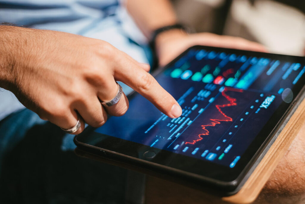 A person uses a finger to interact with a tablet screen displaying financial data, graphs, and stock market charts from 5StarsStocks.com, exploring options for building passive stocks income. | 5StarsStocks