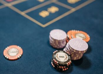 A detailed view of poker chips on a blue gaming table, perfect for gambling themes.